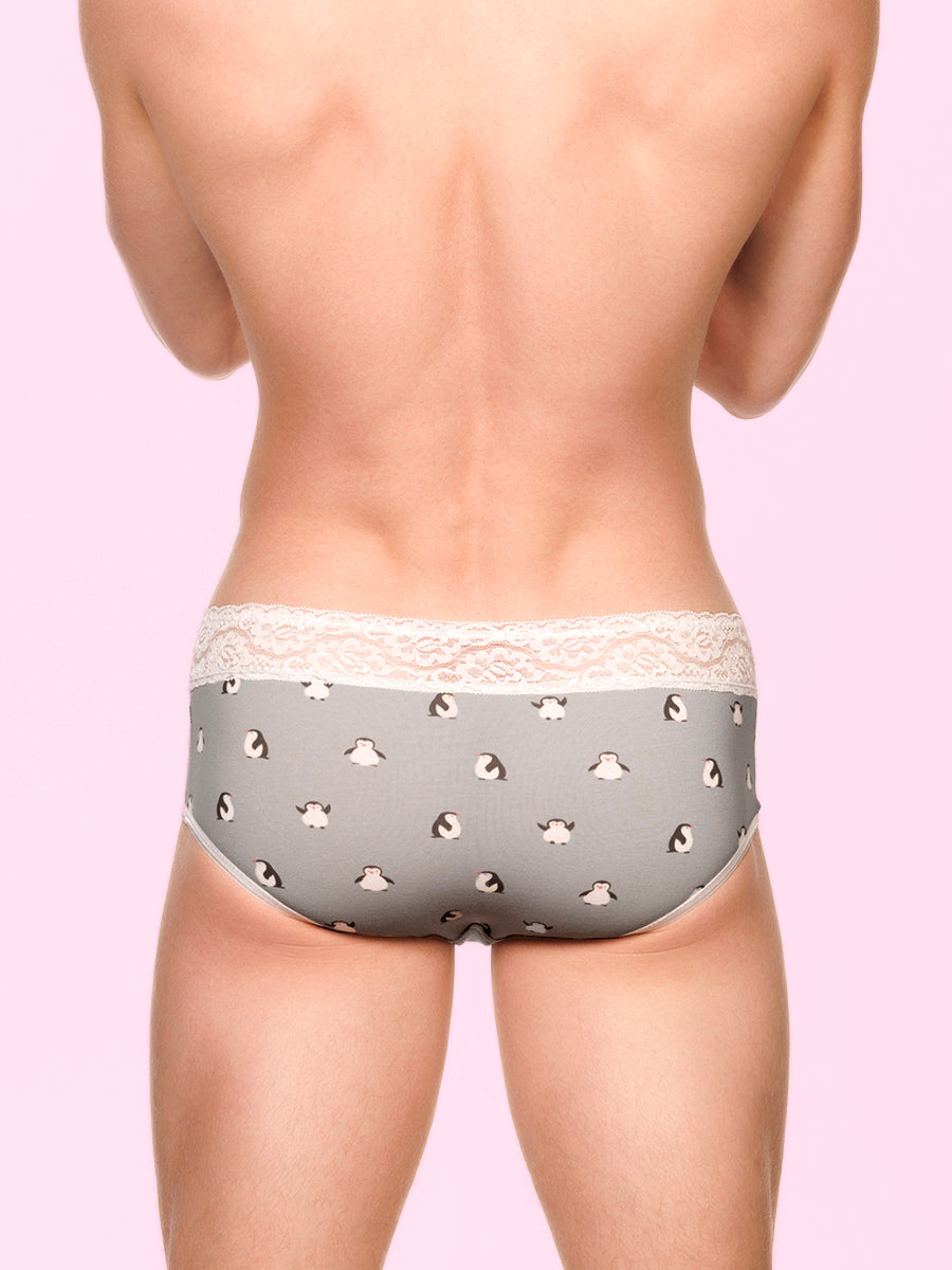 Back view of a man wearing grey XDress panties with white lace trim and penguin pattern against pink background