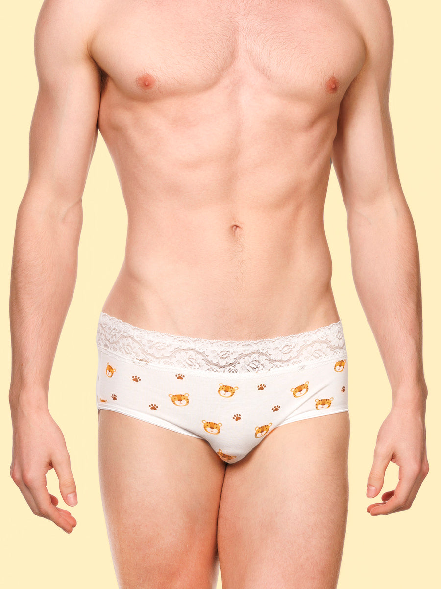 Front view of a man wearing white XDress panties with lace trim and tiger pattern against a yellow background