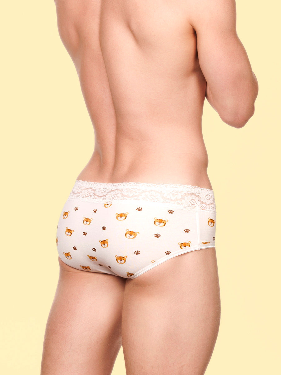 Side view of a man wearing white XDress panties with lace trim and tiger pattern against a yellow background