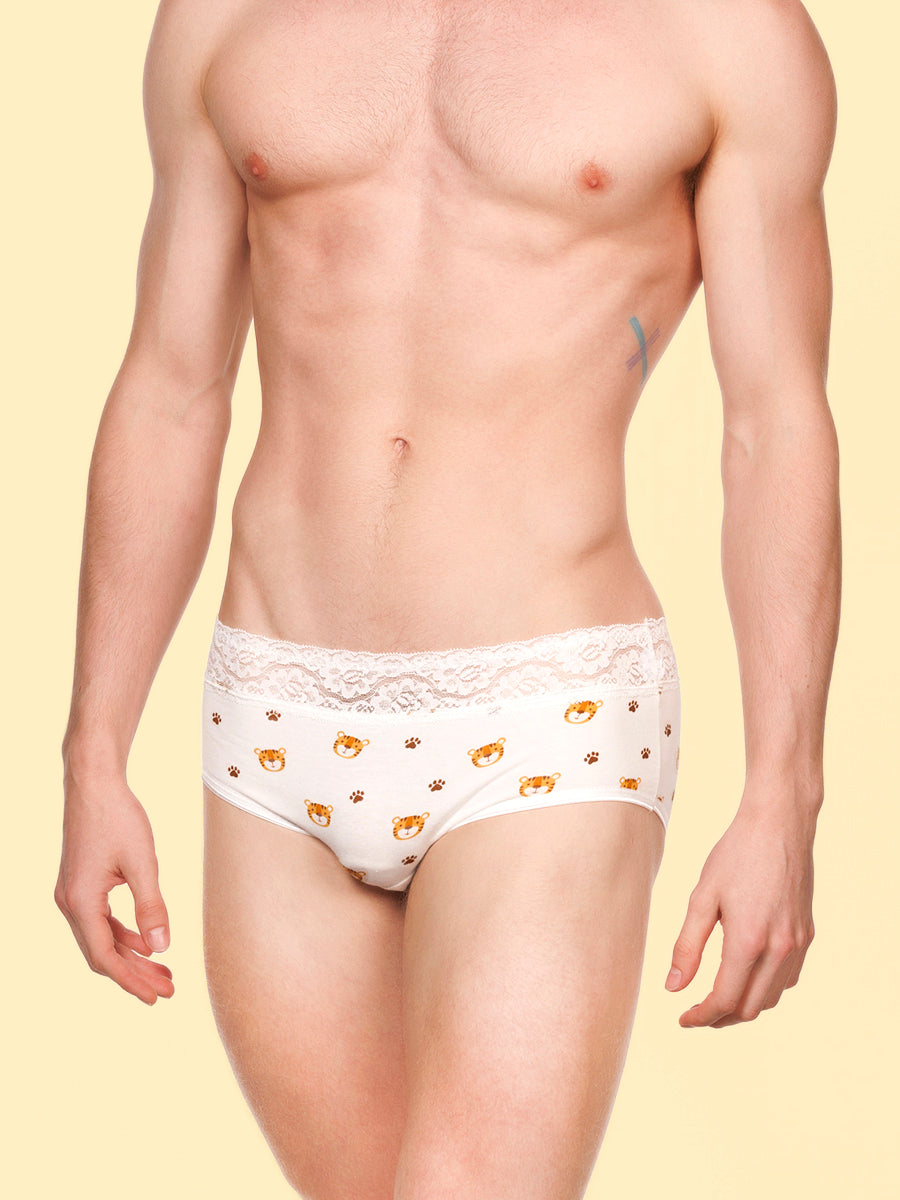 Front view of a man wearing white XDress panties with lace trim and tiger pattern against a yellow background