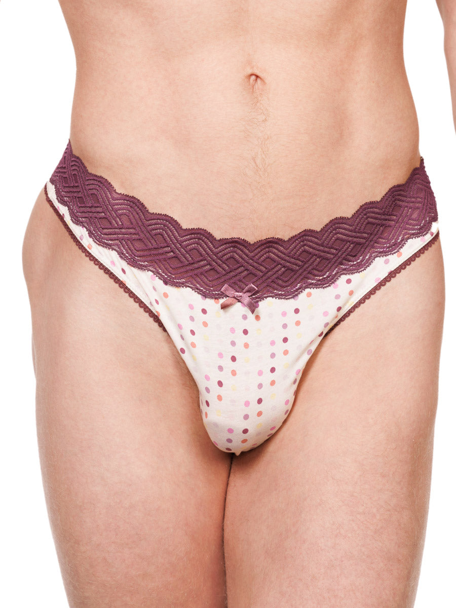 Closeup view of a male model wearing a white XDress cotton thong with polka dots and a burgundy waistband