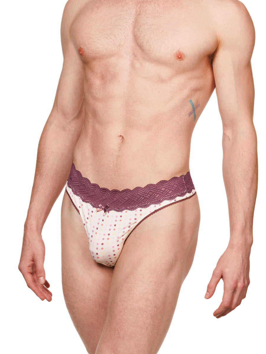 Side view of a male model wearing a white XDress cotton thong with polka dots and a burgundy waistband