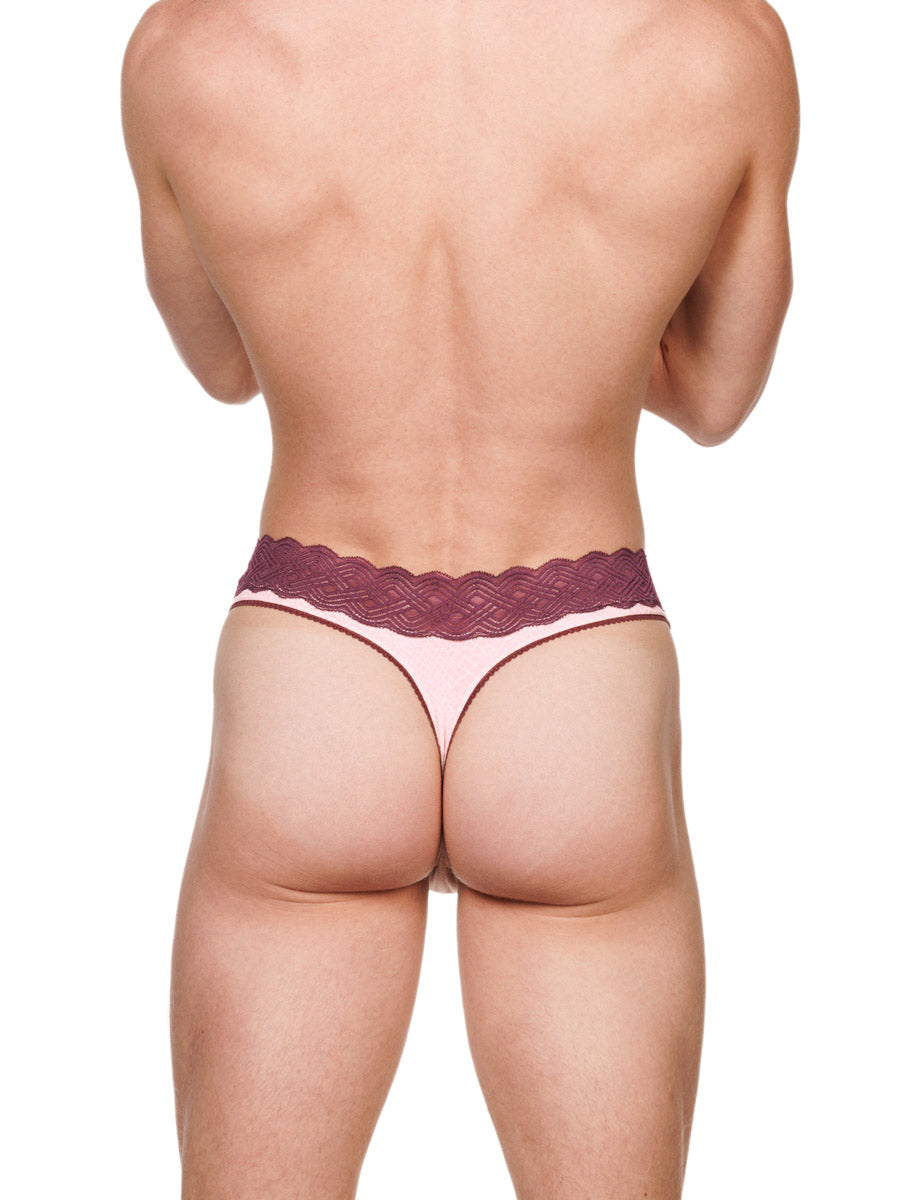 Back view of a male model wearing a pink XDress cotton thong with a red lace waistband