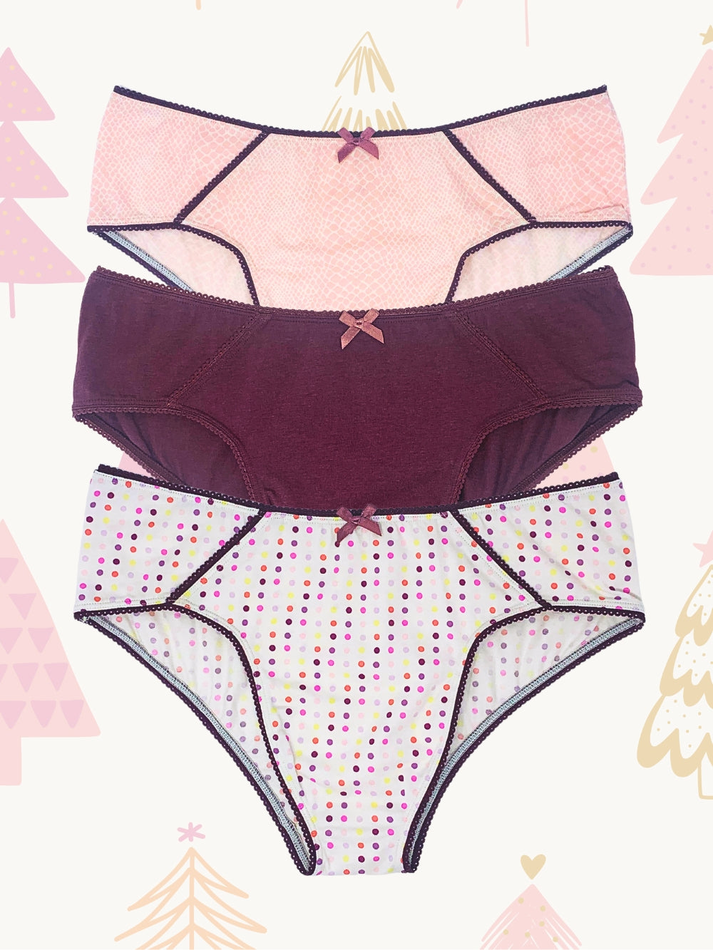 A flat lay image of three XDress hipster panties in pink, burgundy, and white with polka dots