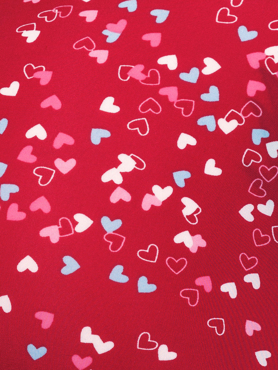 Closeup view of red fabric showing a multicolored heart pattern