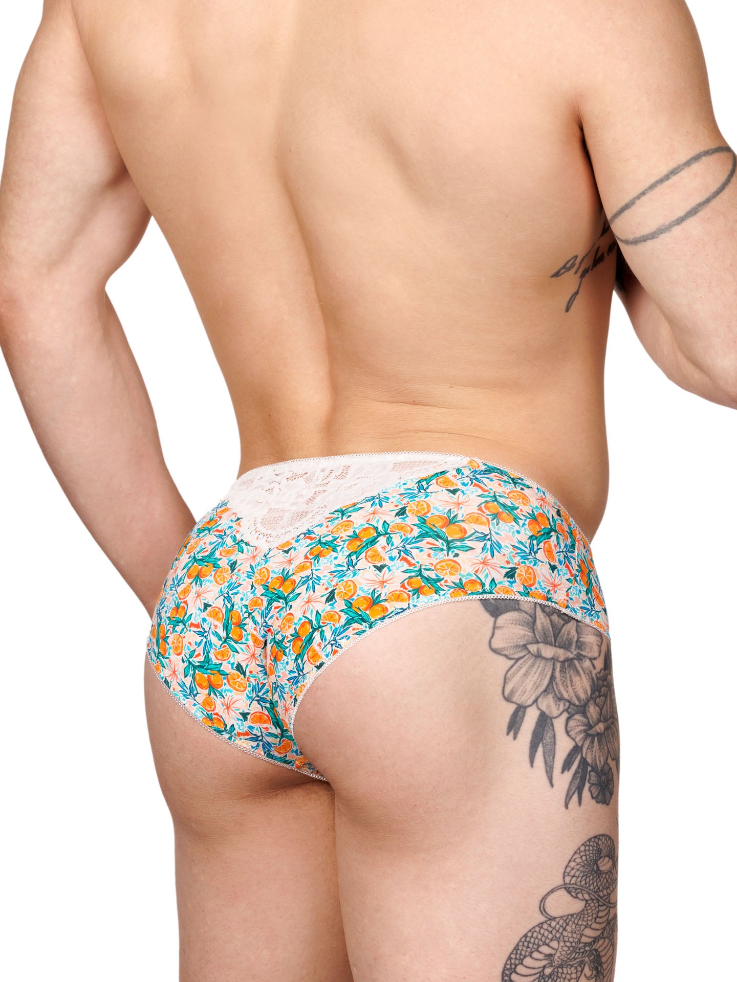 Back side view of a male model wearing XDress men's panties with a vibrant orange blossom pattern.