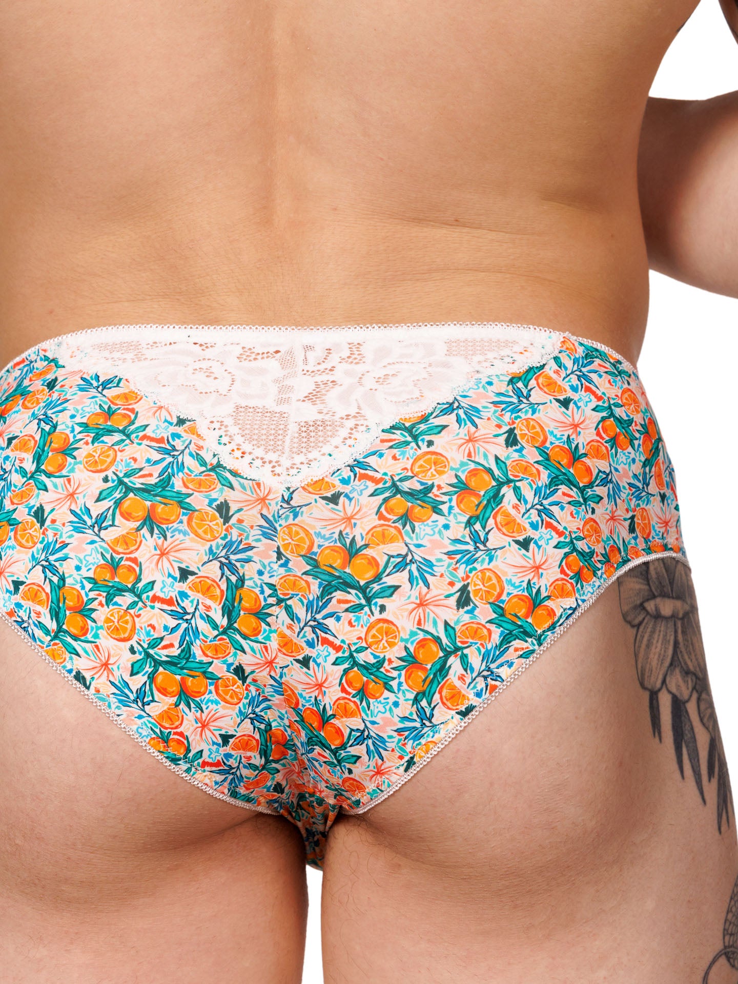 Closeup rear view of a male model wearing XDress men's panties with a vibrant orange blossom pattern.