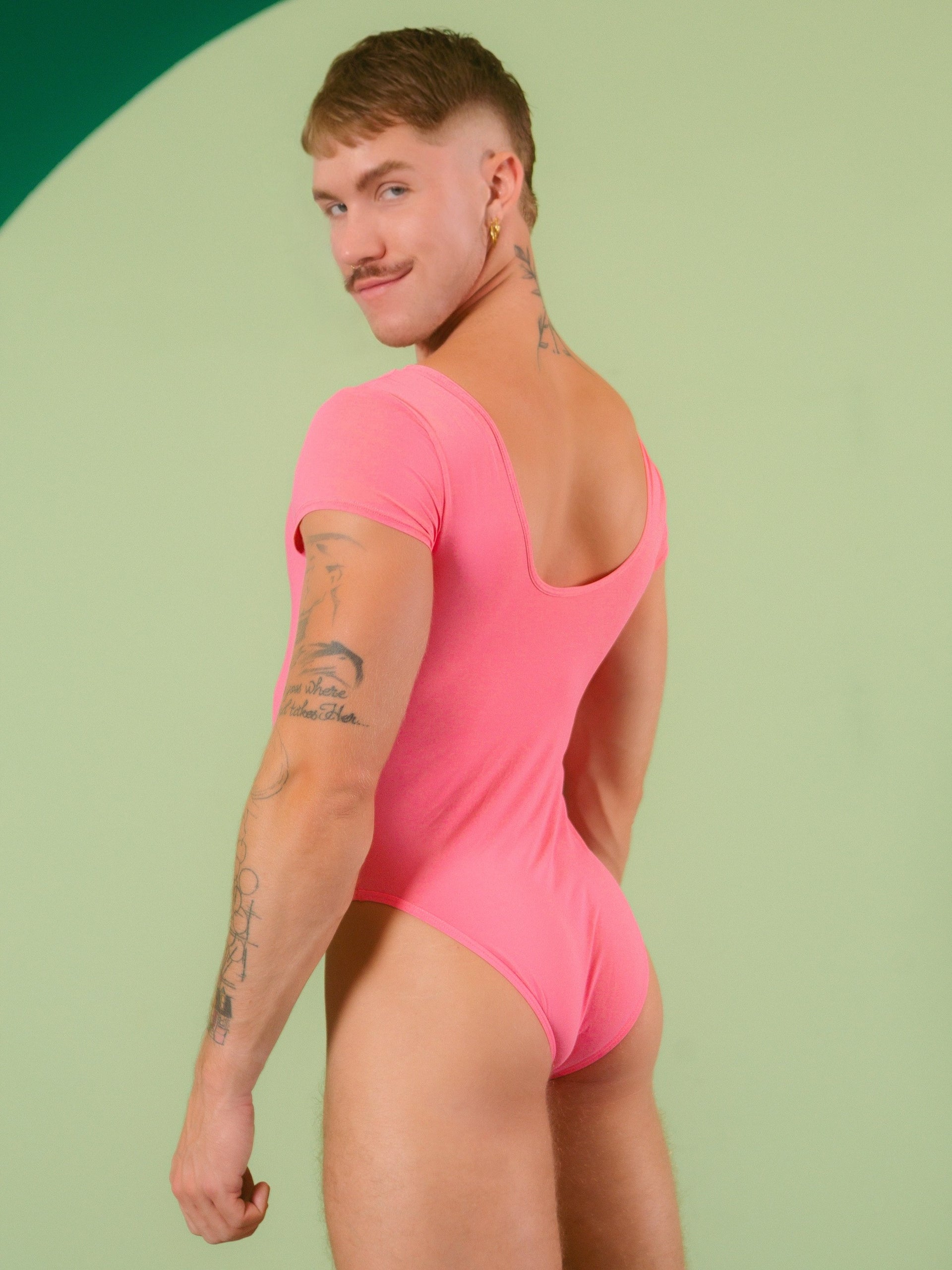 Person wearing a pink bodysuit against a light green background