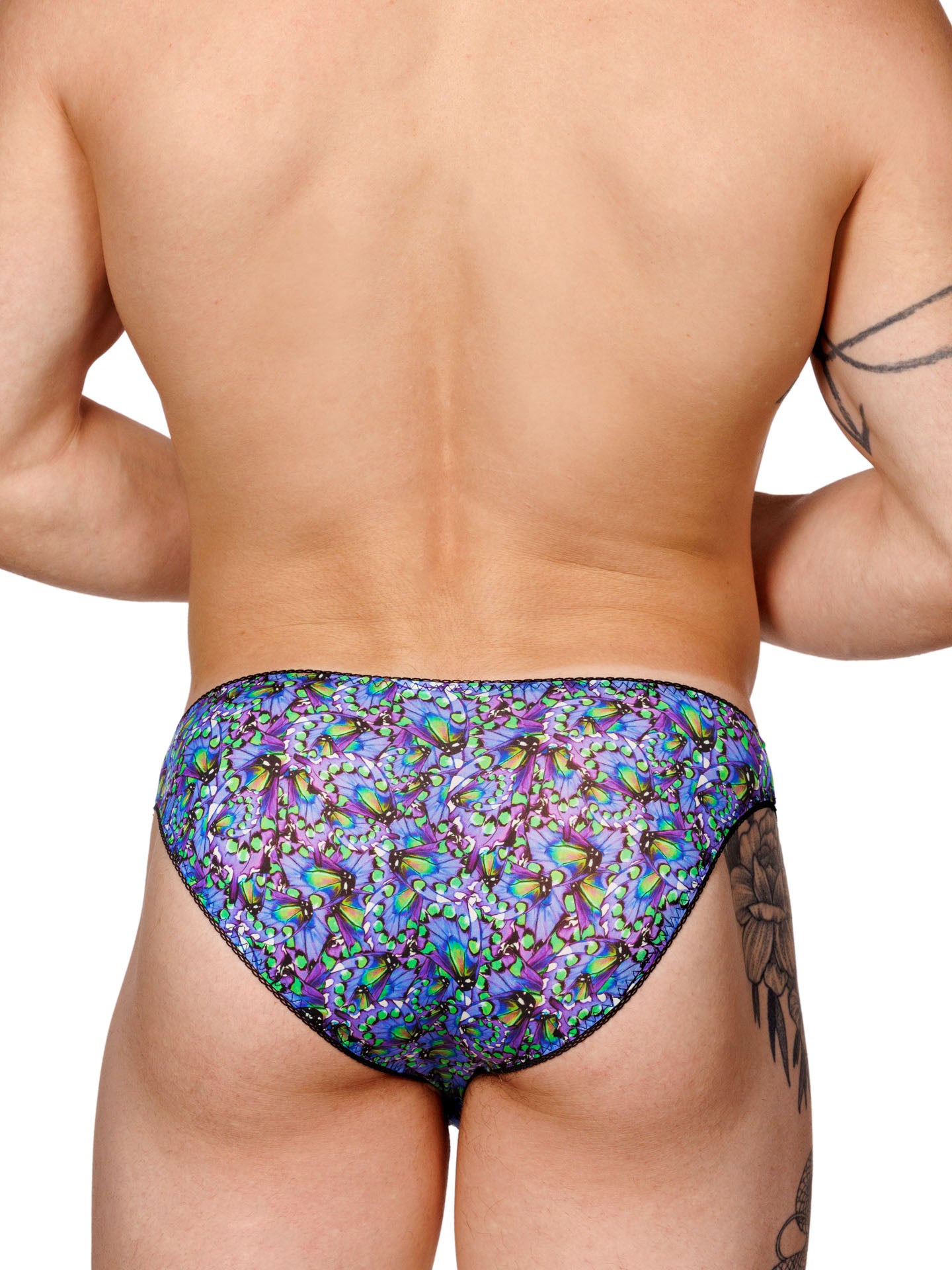 Male model wearing a blue floral print men's panty with lace trim and a metallic charm at the front, shown from the back.