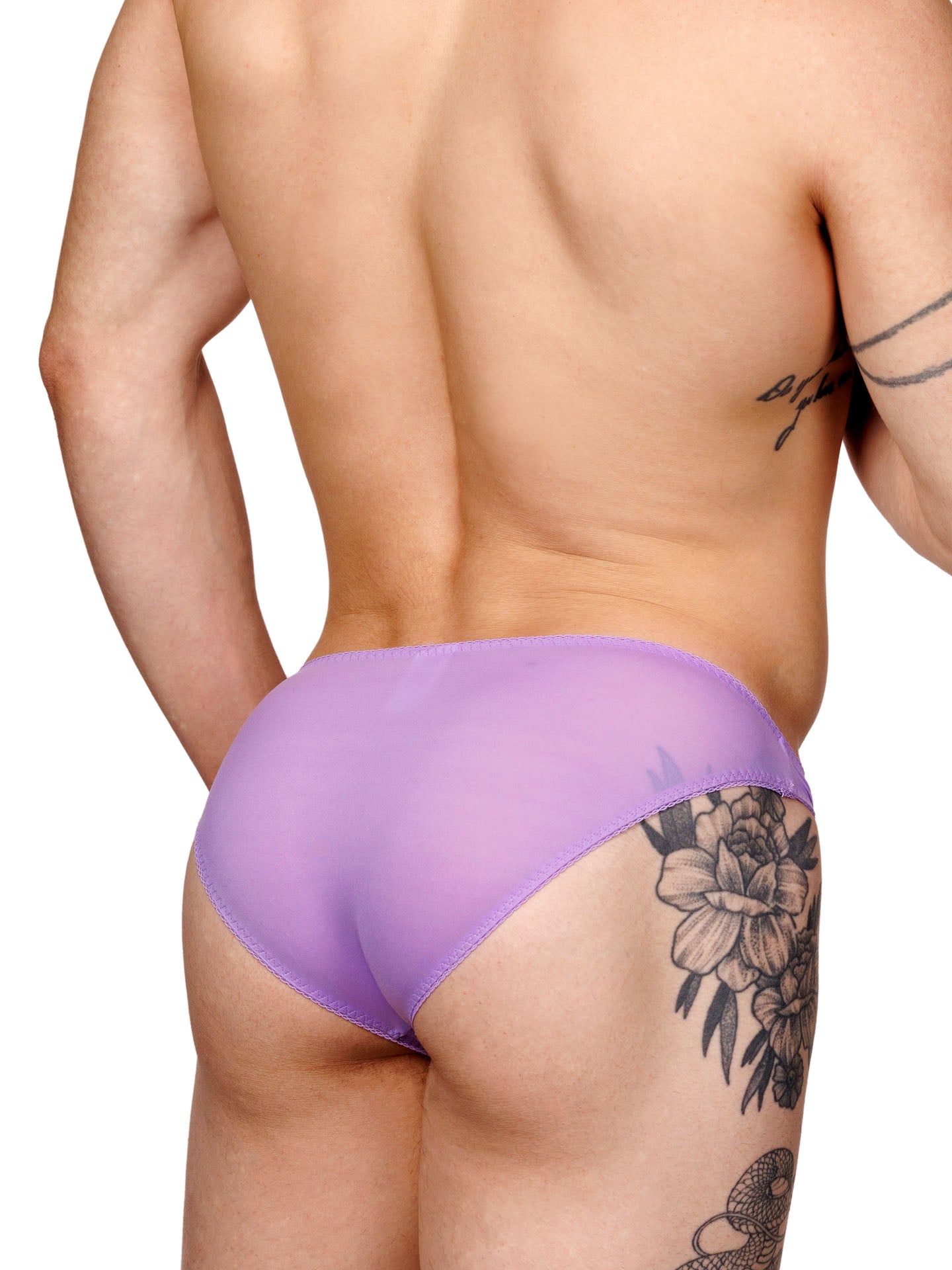 Male model wearing a purple men's panty with lace trim and a metallic charm at the front, shown from the back side.