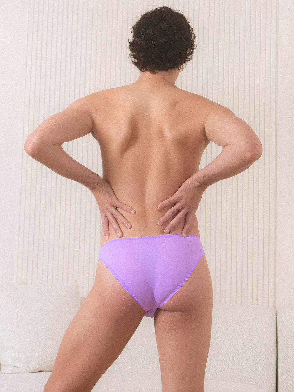 Back view of a male model wearing a purple XDress panty with matching lace trim