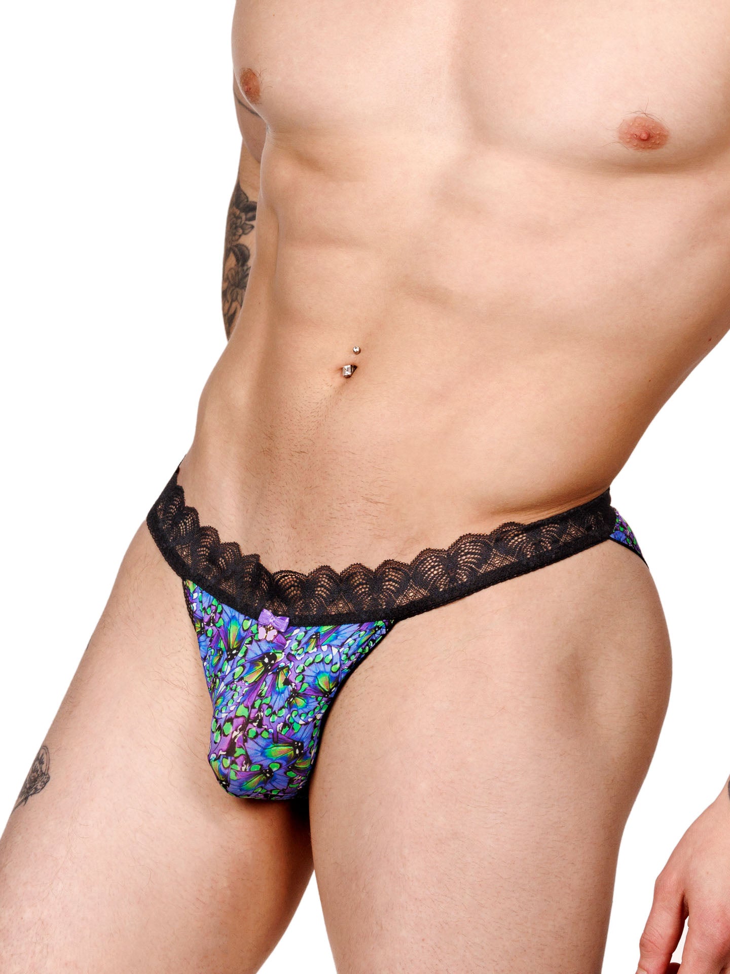 Male model wearing a blue floral print men's bikini panty with a black lace waistband and metallic charm at the front, shown from the side.