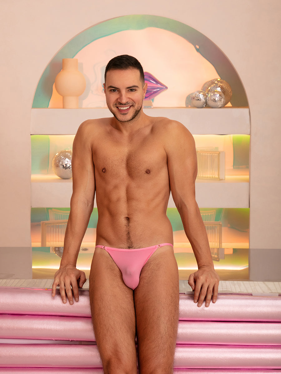 A man wearing pink XDress men's panties, leaning against a counter.