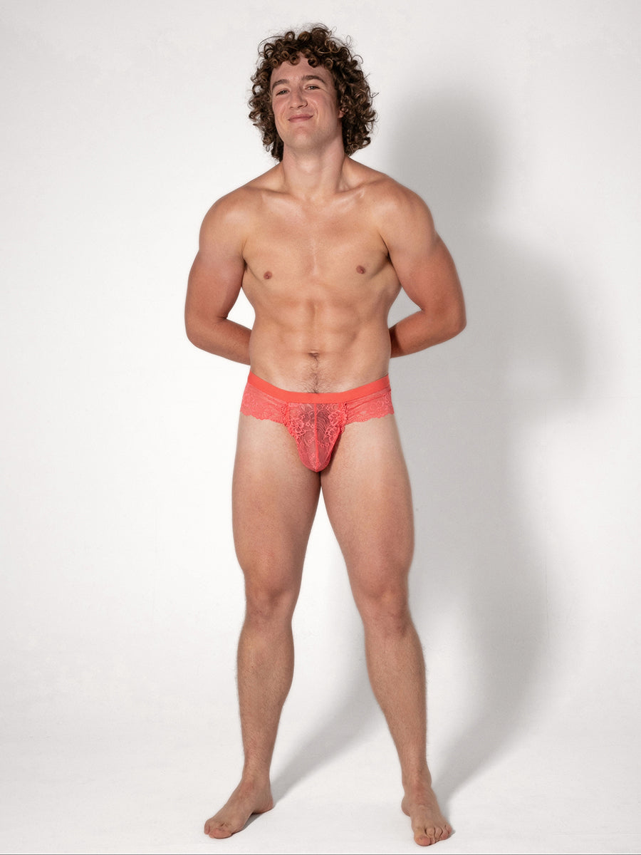 Man wearing coral lace underwear on a white background