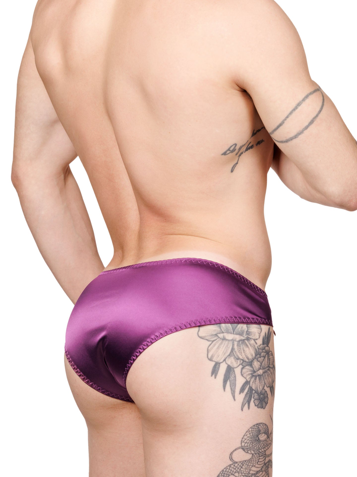 Back view of a male model wearing purple XDress panties with matching bows