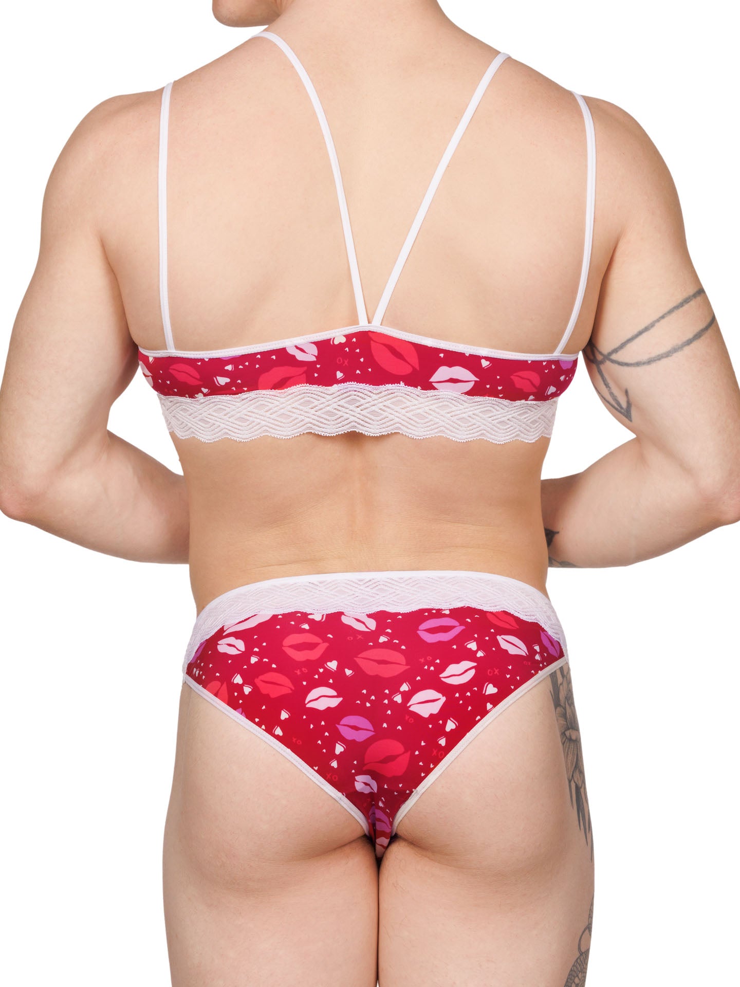 Back view of a male model wearing an XDress matching red and white men's panty and bra with lipstick kisses pattern and lace waistband