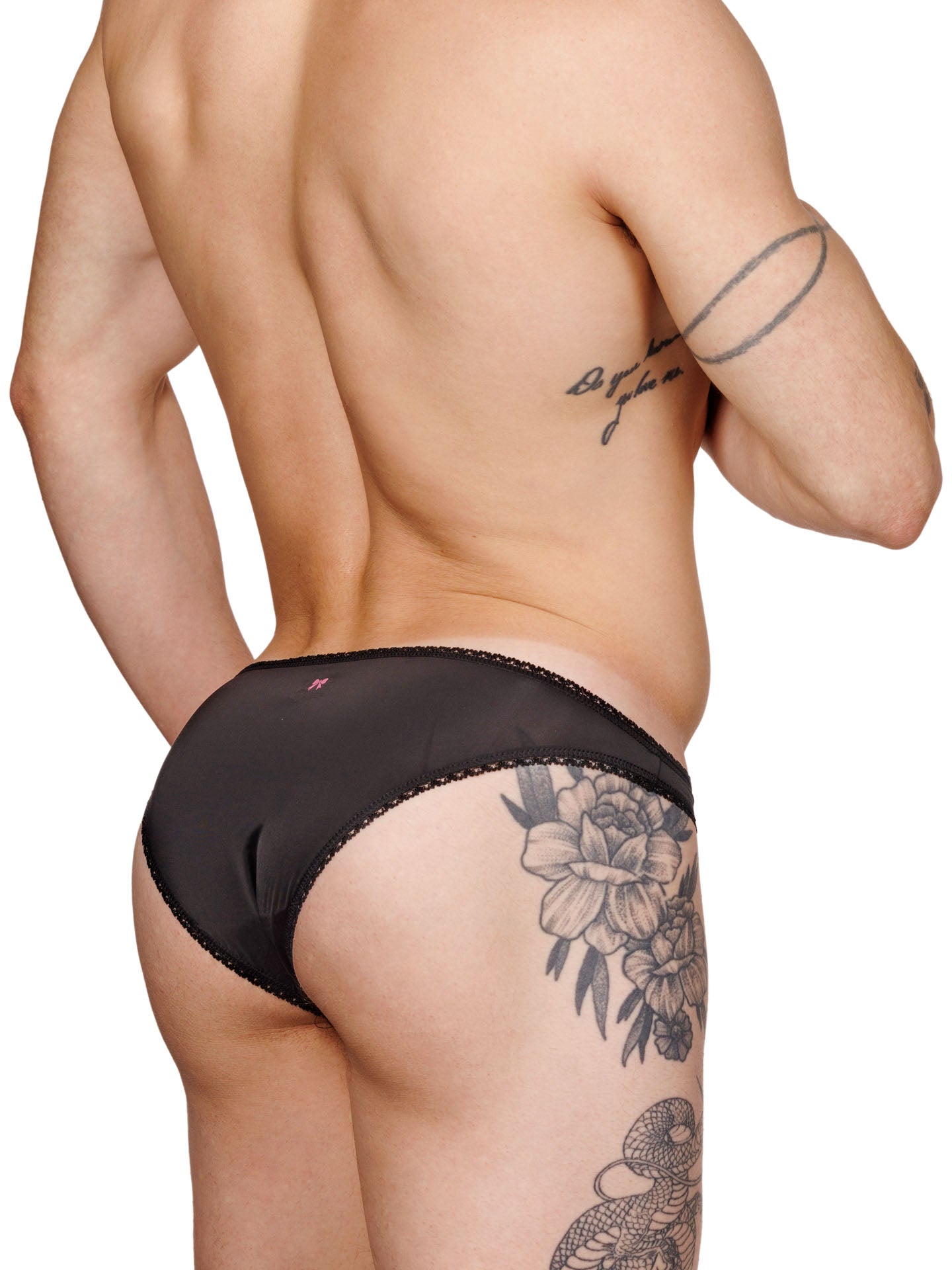 Back view of a male model wearing black lace XDress panties with satin bow